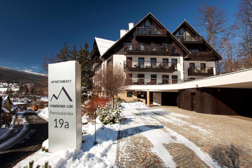 un cartello nella neve davanti a un edificio di Apartamentowiec Panorama Gór City Center Family&Pet-friendly a Szklarska Poręba