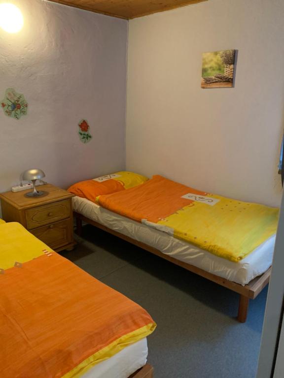 2 camas en una habitación pequeña con sábanas amarillas y naranjas en La Pergola, en Avegno