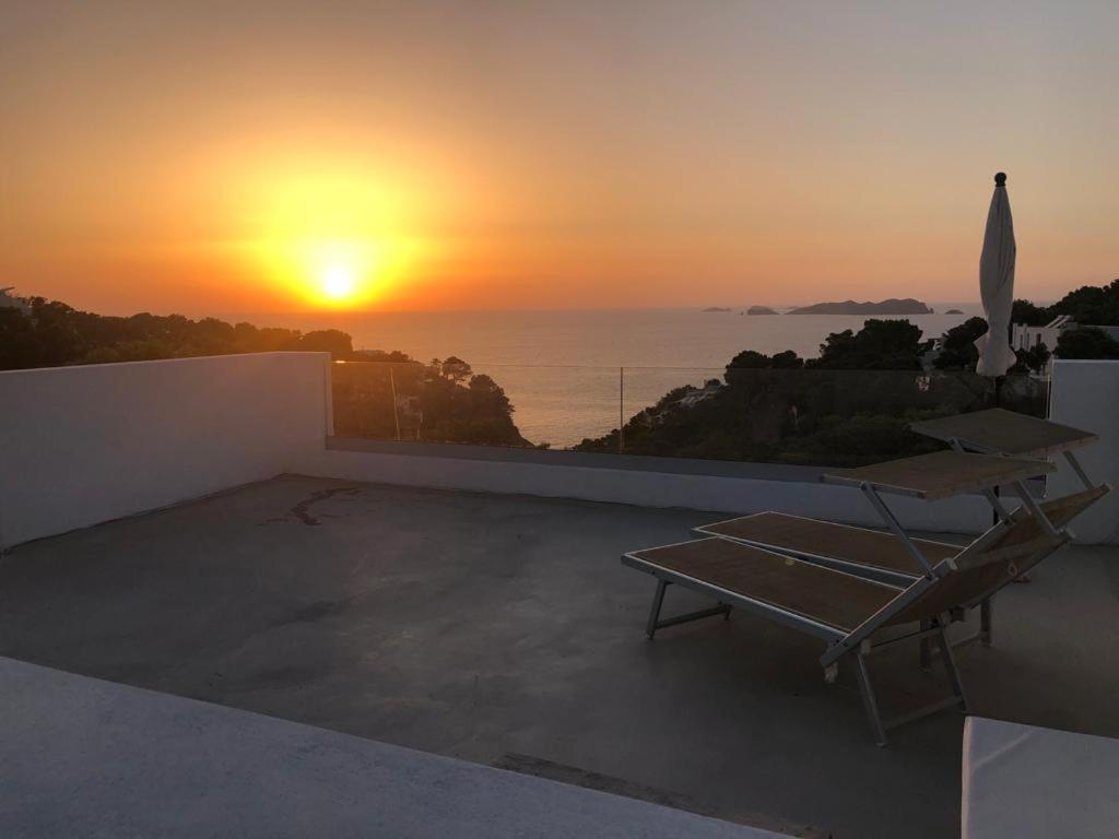 a sunset on a rooftop with a table and an umbrella at CASA ANA in Sant Josep de sa Talaia