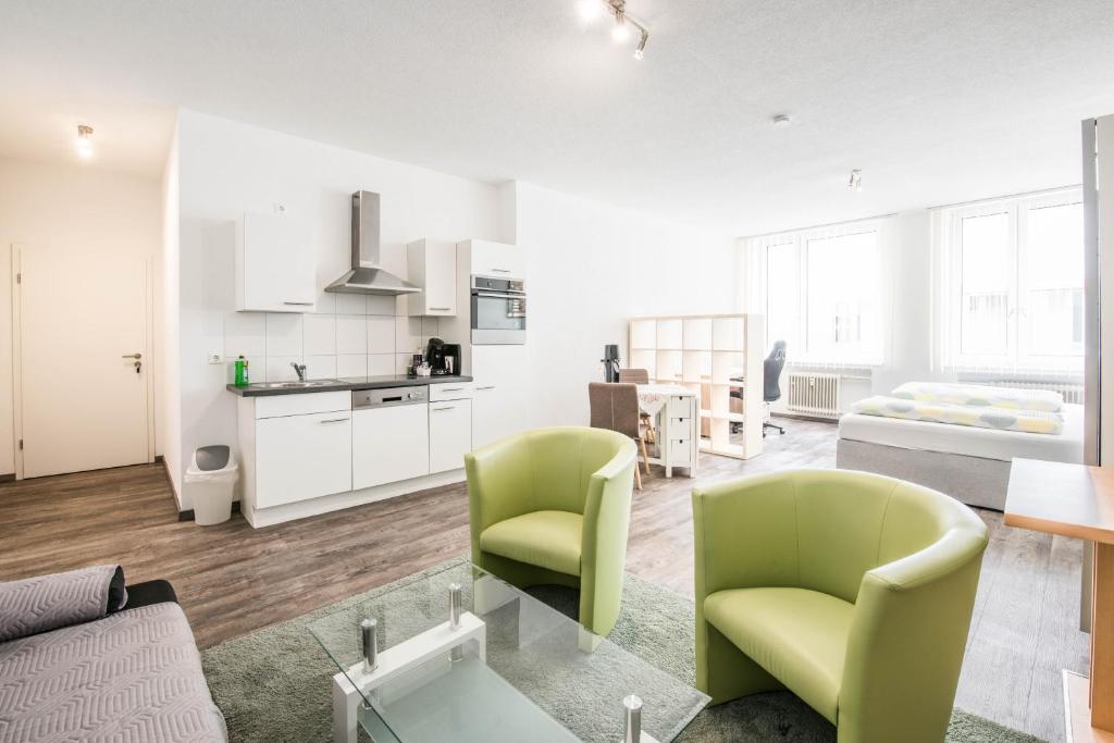 a living room with green chairs and a kitchen at Apartmenthaus Aalen in Aalen