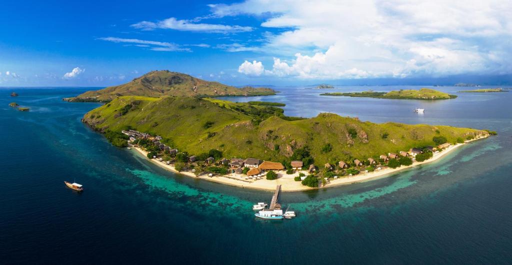 une île dans l'océan avec un bateau dans l'établissement Komodo Resort, à Sebayur