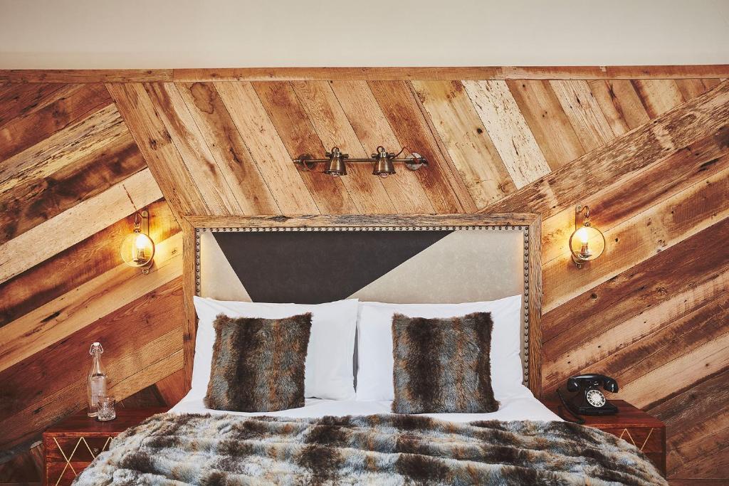a bedroom with a bed with a wooden wall at No.26 By The Sea in Oban