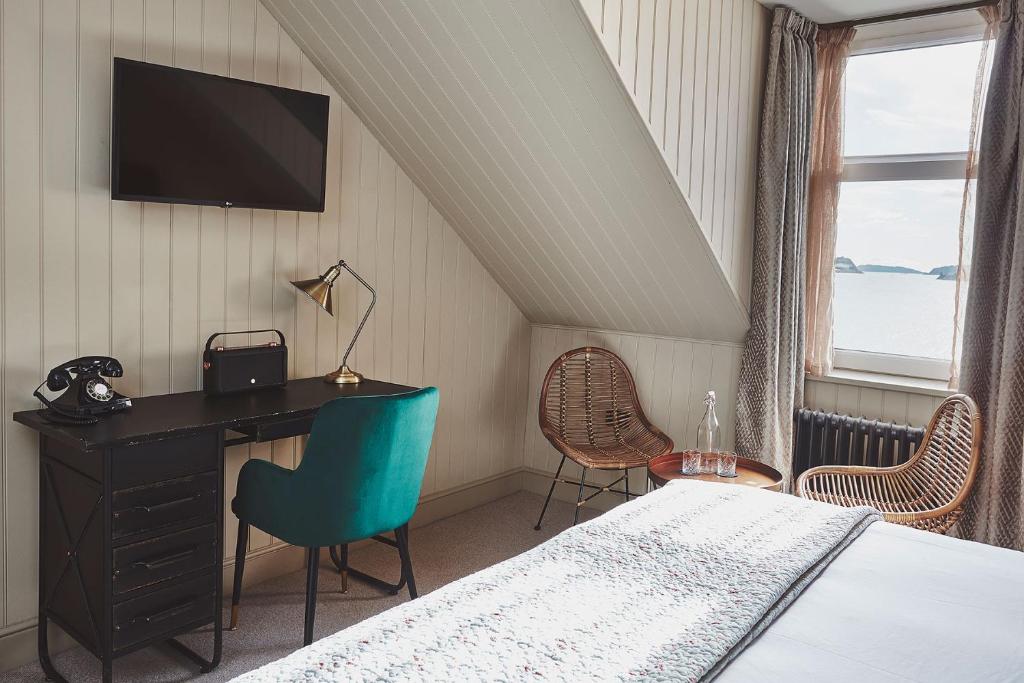 a bedroom with a bed and a desk and chairs at No.26 By The Sea in Oban