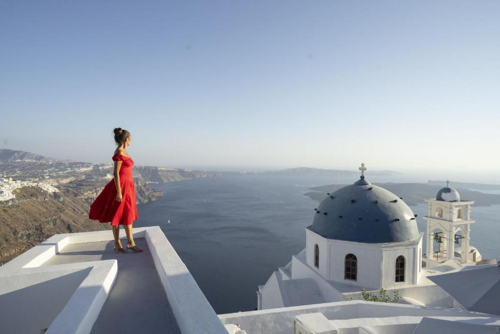 a woman in a red dress standing on top of a building at Imer Villas in Imerovigli