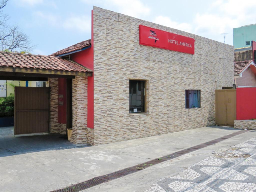 a building with a red sign on the side of it at Hotel America in Jacareí