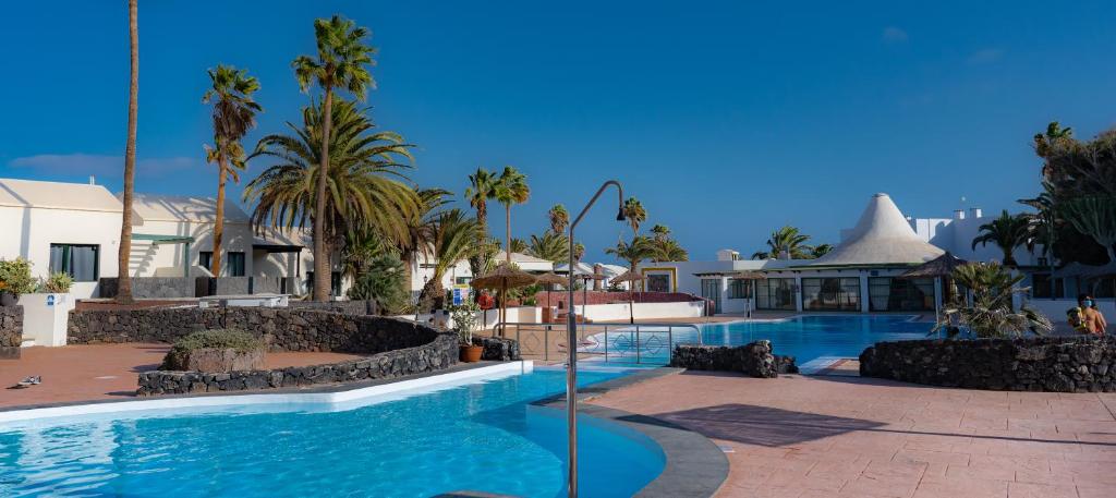 une piscine dans un complexe avec des palmiers et des bâtiments dans l'établissement Beautiful studio on the seafront, à Costa Teguise