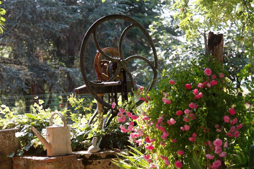 eine Metallskulptur in einem Garten mit rosa Blumen in der Unterkunft Gîte de Tarou in Labastide-de-Lévis