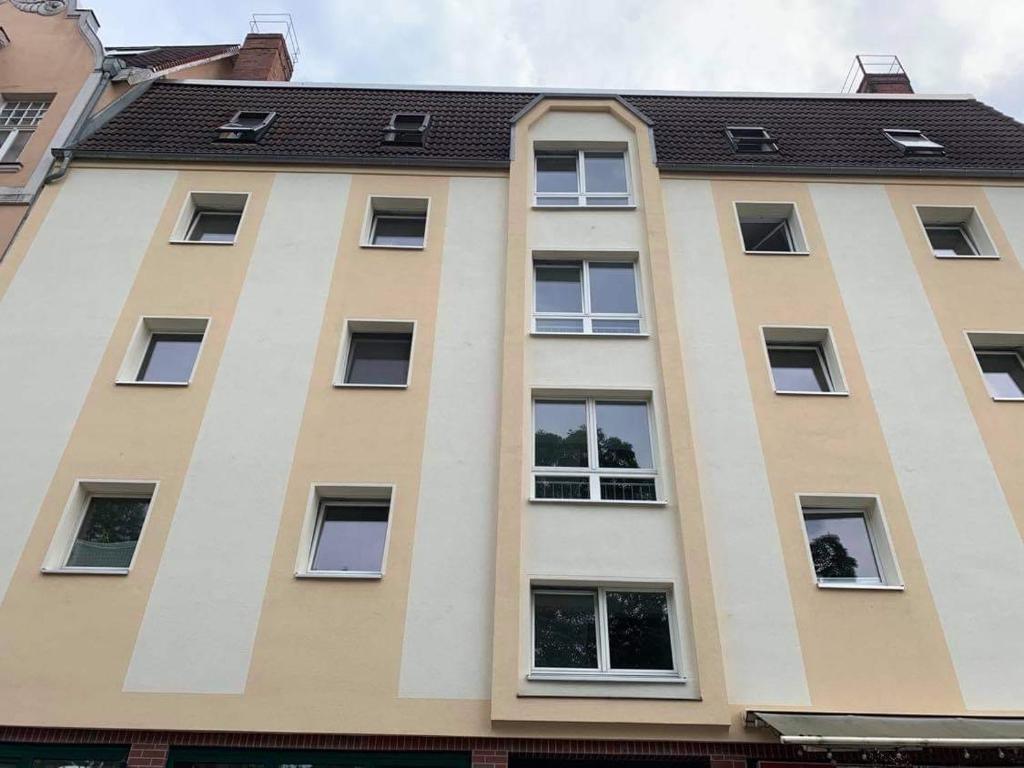 um edifício alto com janelas e um telhado em TOP LAGE 2 Zimmerwohnung mit Balkon und bester Aussicht in OG 2 links em Rostock