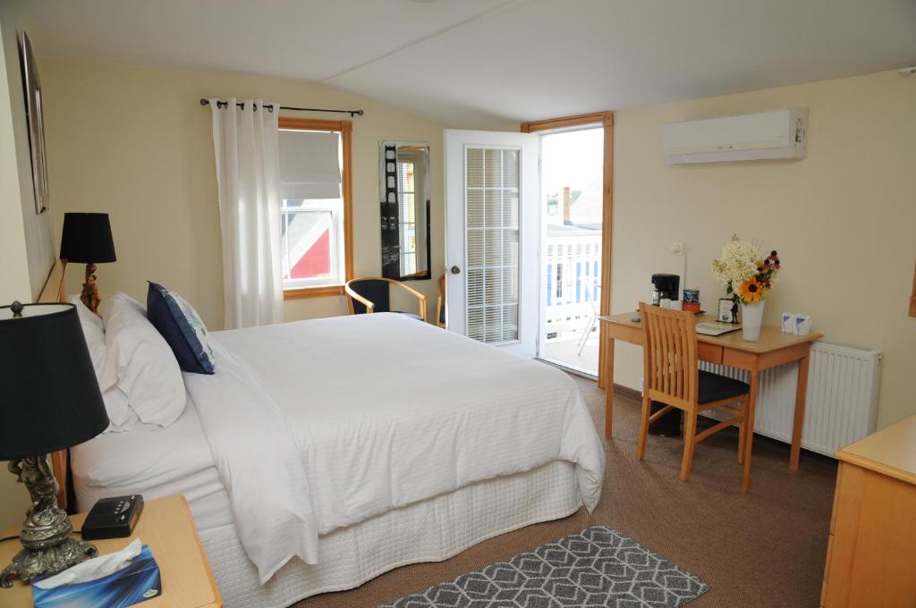 a bedroom with a white bed and a desk and a table with a chair at Smugglers Cove Inn in Lunenburg