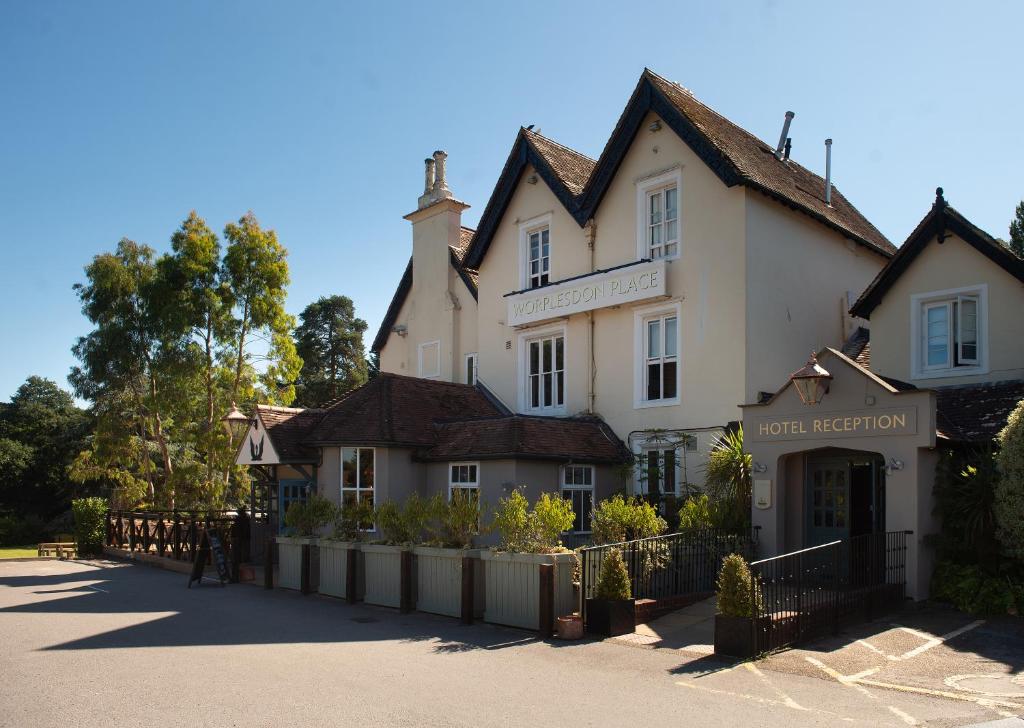 un edificio blanco con una valla delante en Worplesdon Place Hotel, en Guildford