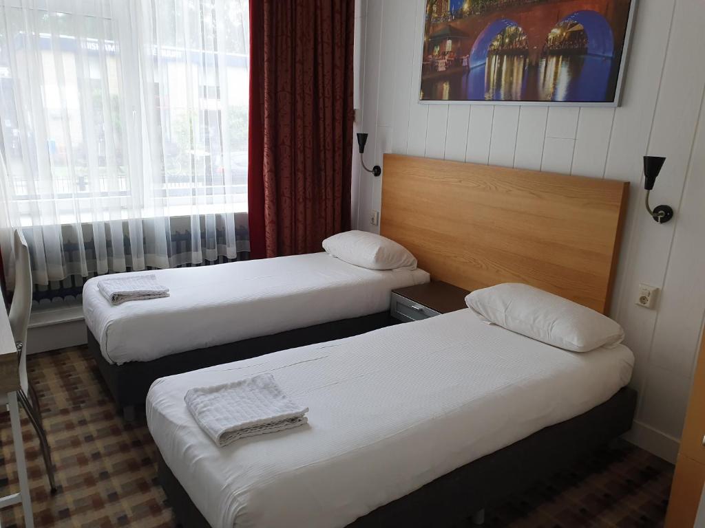 a hotel room with two beds and a window at Hotel Holland Lodge in Utrecht