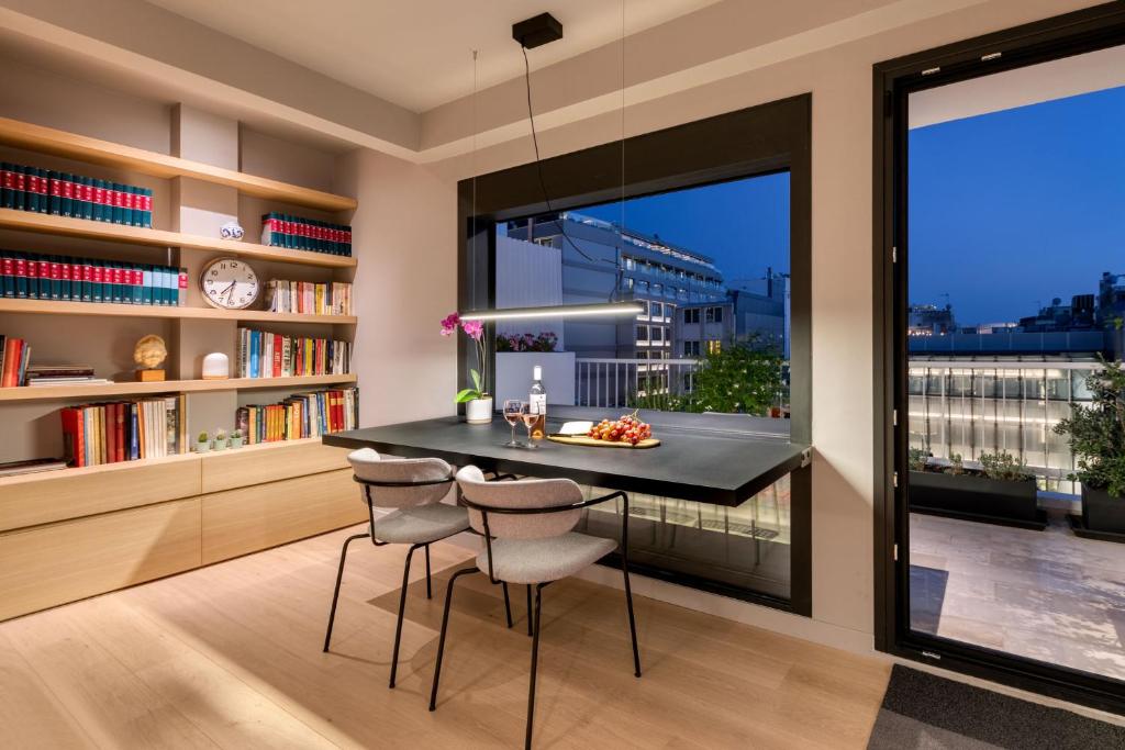 jadalnia ze stołem i krzesłami oraz dużym oknem w obiekcie Central Athens Penthouse w Atenach