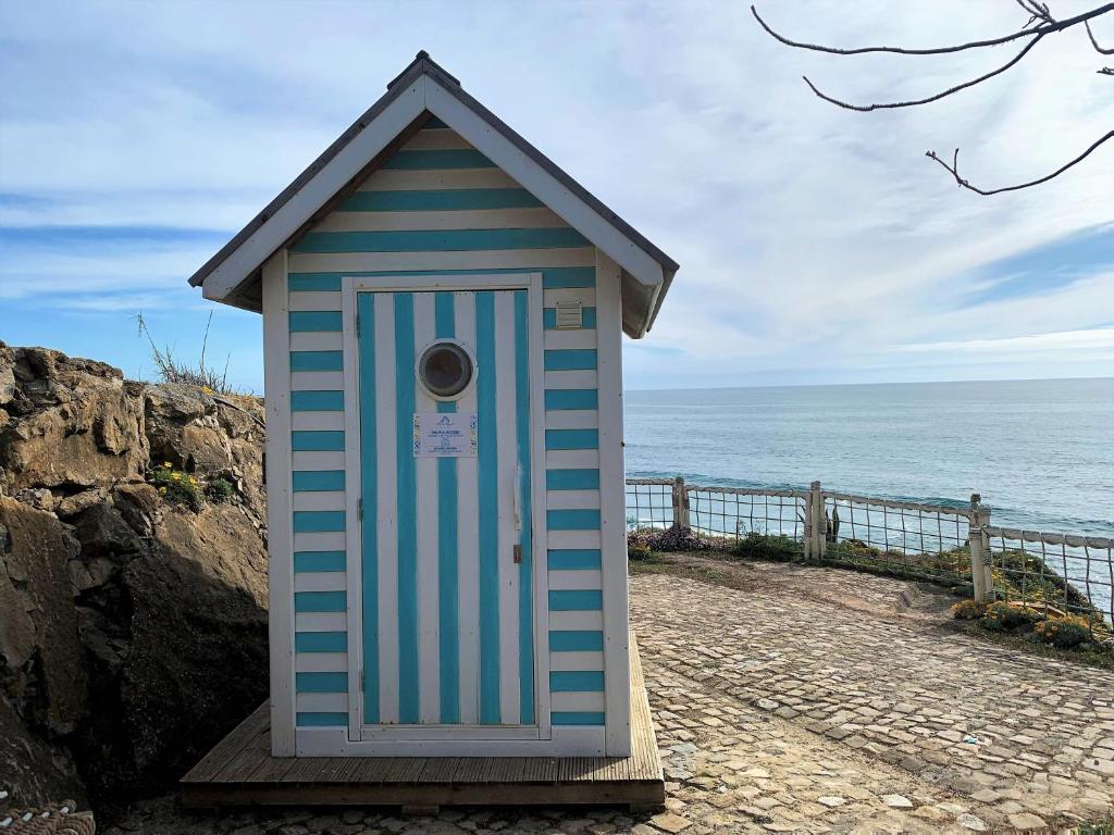 a blue and white shack on the side of the ocean at Villa Ana Margarida Beach in Ericeira