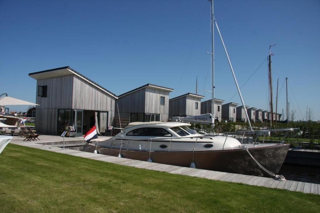 a boat is docked in a marina next to houses at Vakantie studio Heeg met eigen ligplaats in Heeg