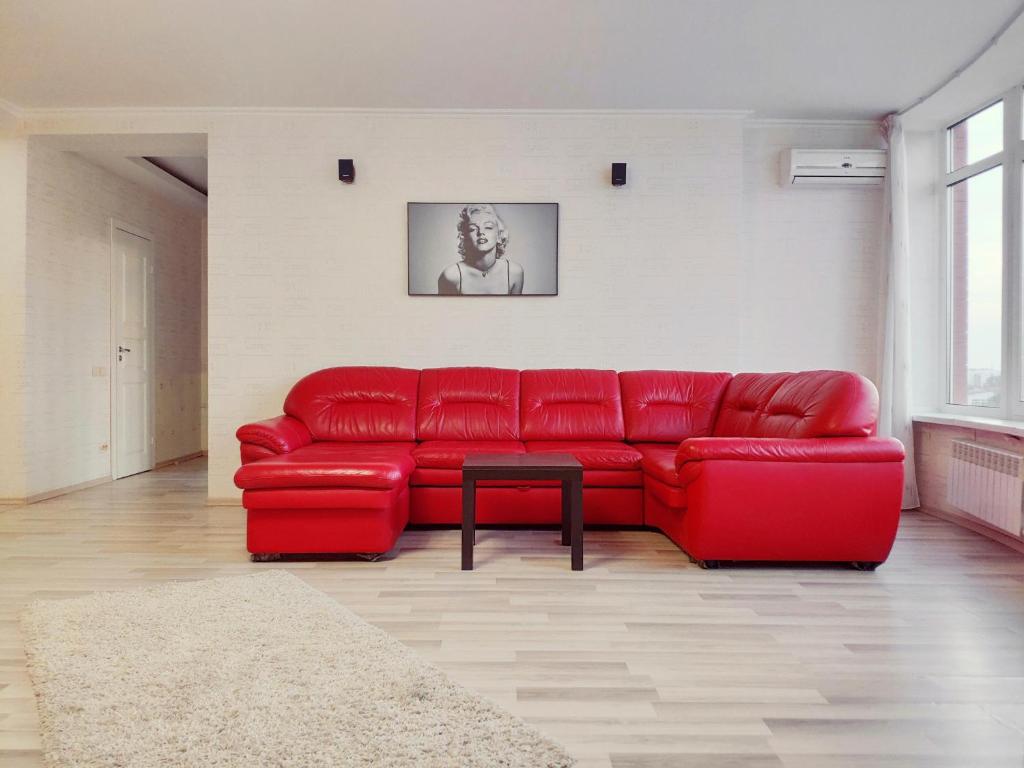 a red couch in a living room with a table at ПЕНТХАУС 110 м2 в САМОМ ЦЕНТРЕ ЯРОСЛАВЛЯ in Yaroslavl