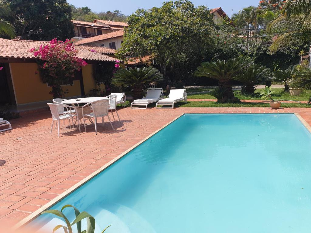 einen Pool mit einem Tisch und Stühlen im Hof in der Unterkunft Pousada Lele do Pero in Cabo Frio