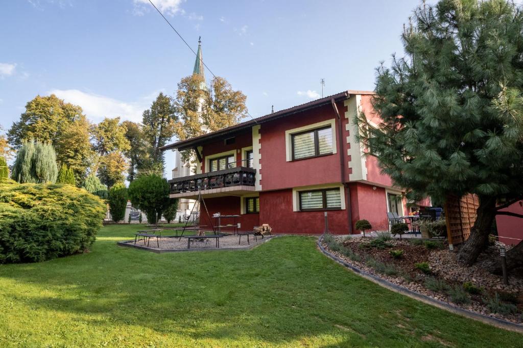 ein rotes Haus mit einem Balkon und einem Hof in der Unterkunft Villa Jurka in Paszkówka