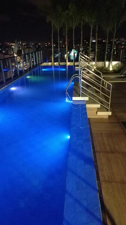 a swimming pool with blue lights in a city at night at Time Apto 410 Quarto Sala Luxo Conforto na Praia Ponta Verde in Maceió