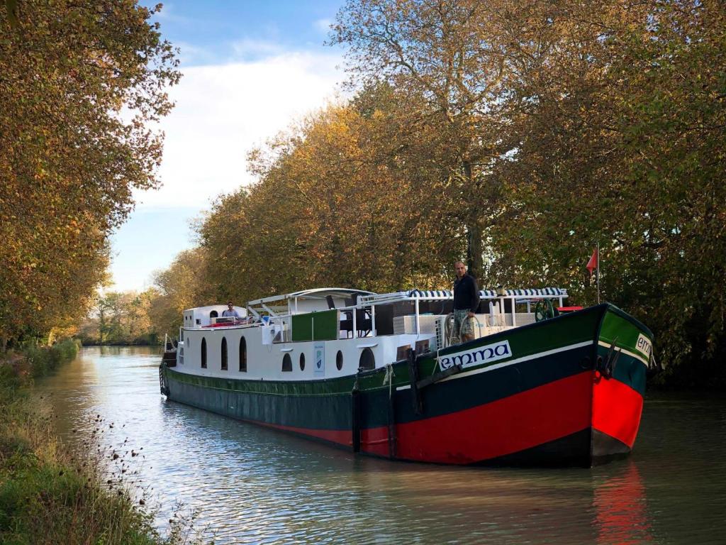 Un homme est debout sur un bateau sur une rivière dans l'établissement péniche Le Black Mountain, à Villepinte