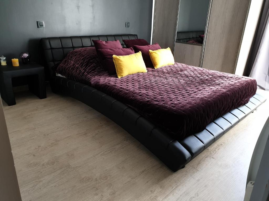 a black bed with yellow and purple pillows on it at Suite privé dans maison de village in Soual
