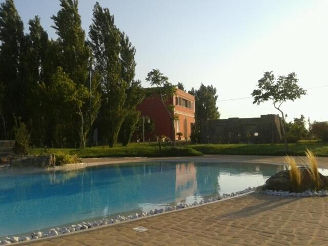 a large swimming pool with a house in the background at Tenuta Monaci La Murra in Carmiano