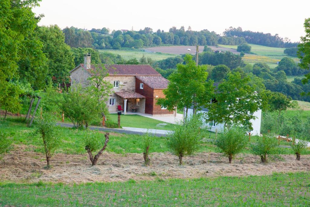 a house in the middle of a field with trees at A Quinta Das Maceiras 