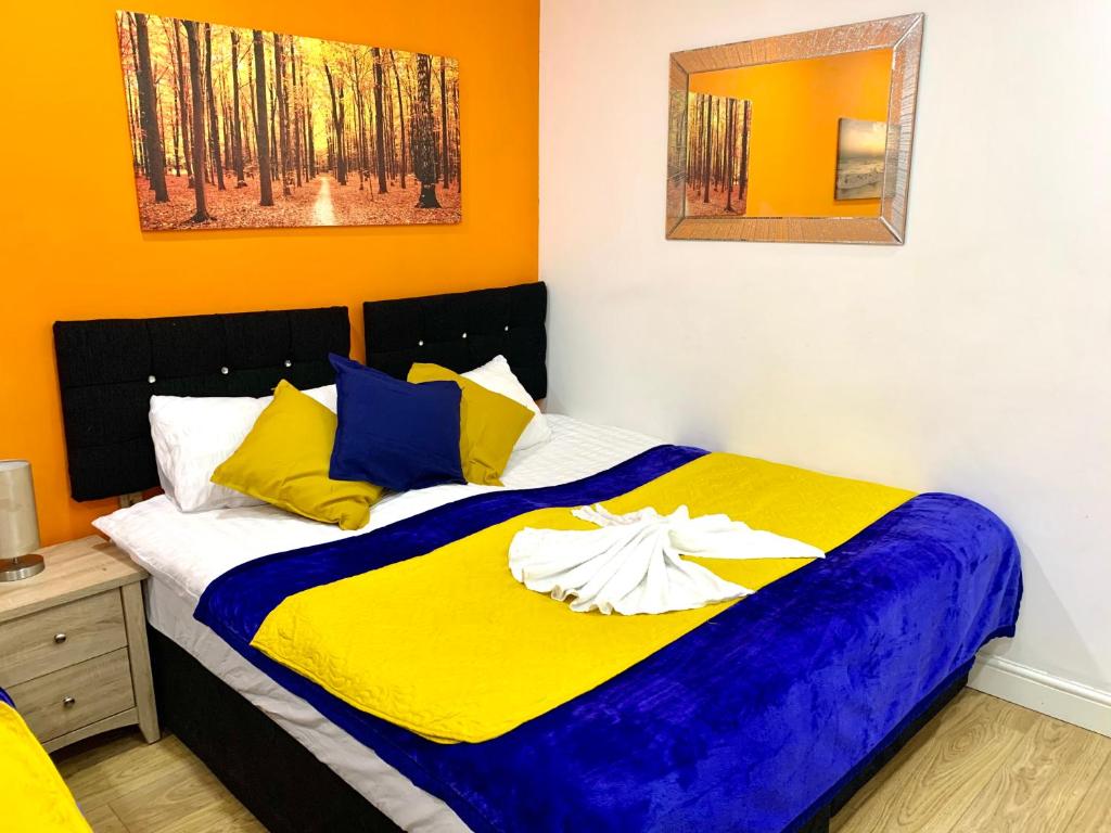 a bedroom with a bed with yellow and blue at London 2 Bedroom Apartment, Kitchen, Reception and Private Garden in London