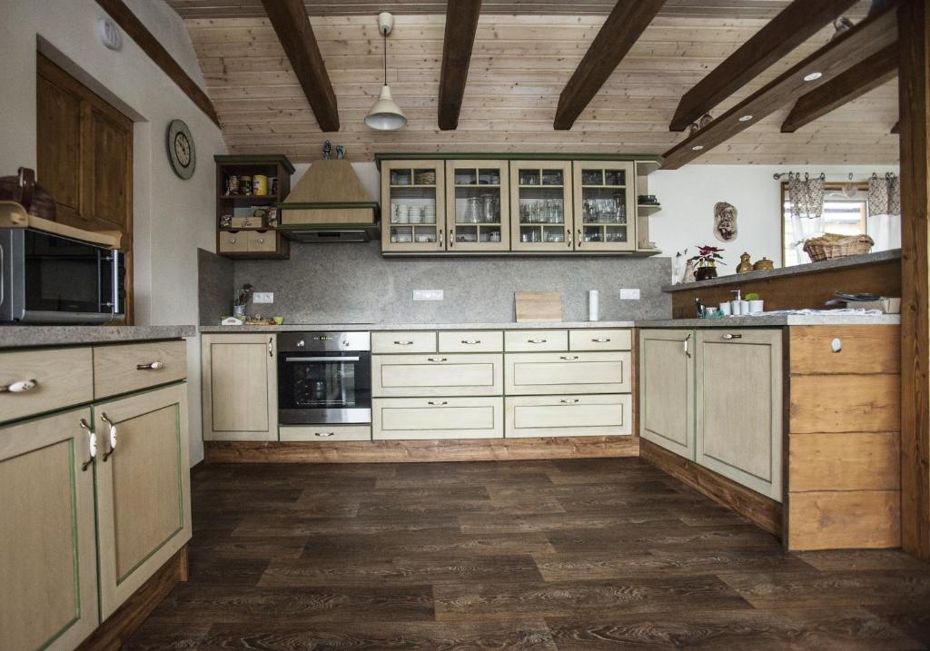 a large kitchen with white cabinets and wooden floors at Ve Stodole in Zlatá Olešnice