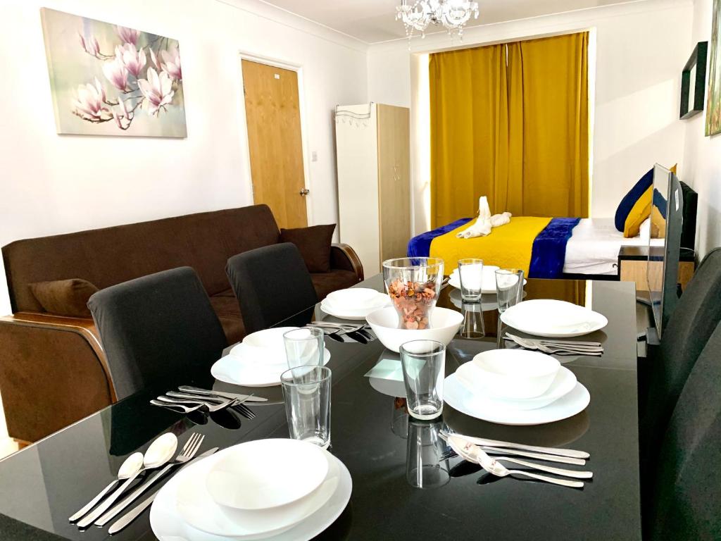 un comedor con una mesa con platos blancos y cubiertos en London 4 Bedrooms 3 Bathrooms with Garden House, en Londres