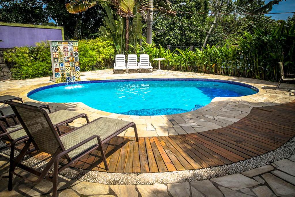 uma piscina com cadeiras e um deque de madeira em VELINN Pousada Catamarã Brasil em Ilhabela
