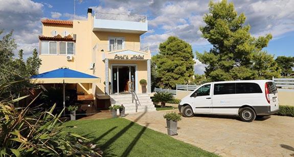 una furgoneta blanca estacionada frente a una casa en Peri's Hotel, en Artemida
