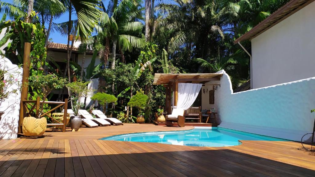 un patio trasero con piscina y terraza de madera en Pousada Burundanga, en Itacaré