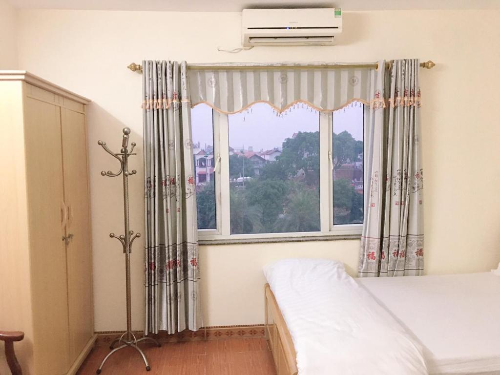 a bedroom with a bed and a large window at KHÁCH SẠN HÀ ANH 1 NỘI BÀI in Noi Bai