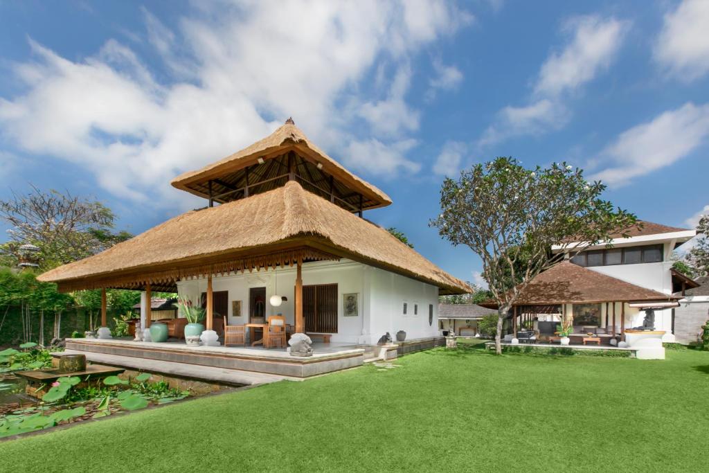 a house with a thatched roof and a yard at Villa Wantilan Putih in Sanur