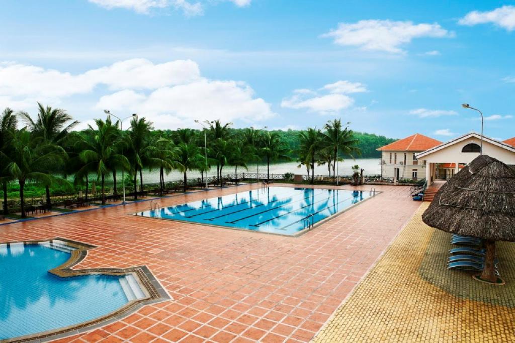 une piscine dans un complexe avec des palmiers en arrière-plan dans l'établissement Vietnam Golf - Lake View Villas, à Hô-Chi-Minh-Ville