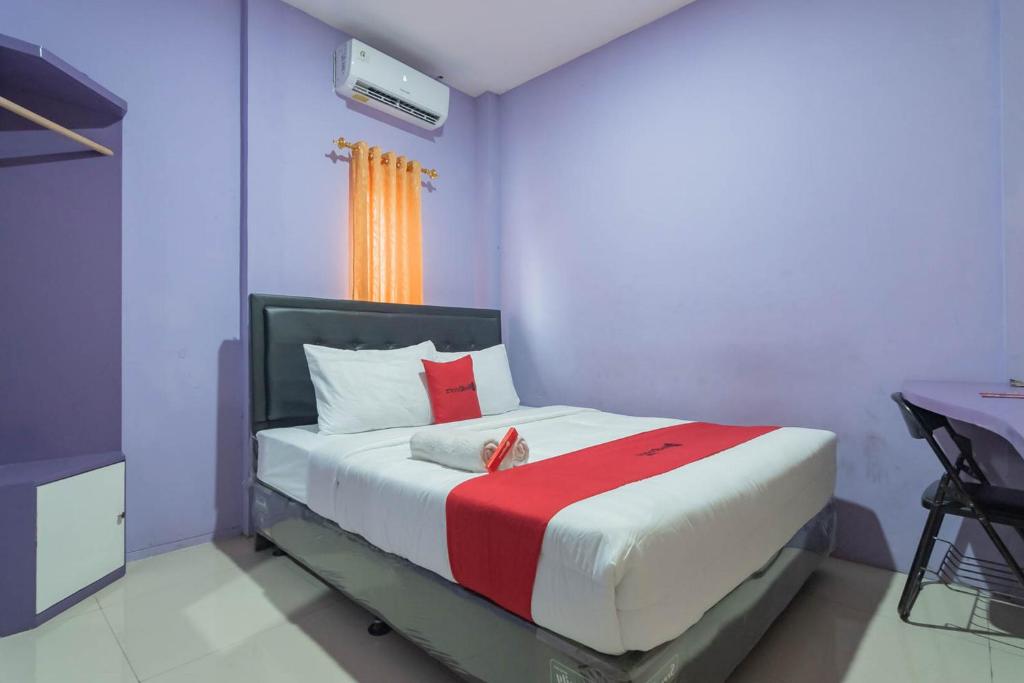 1 dormitorio con 1 cama con manta roja y blanca en RedDoorz @ Gatot Subroto Street Bandung 3, en Bandung