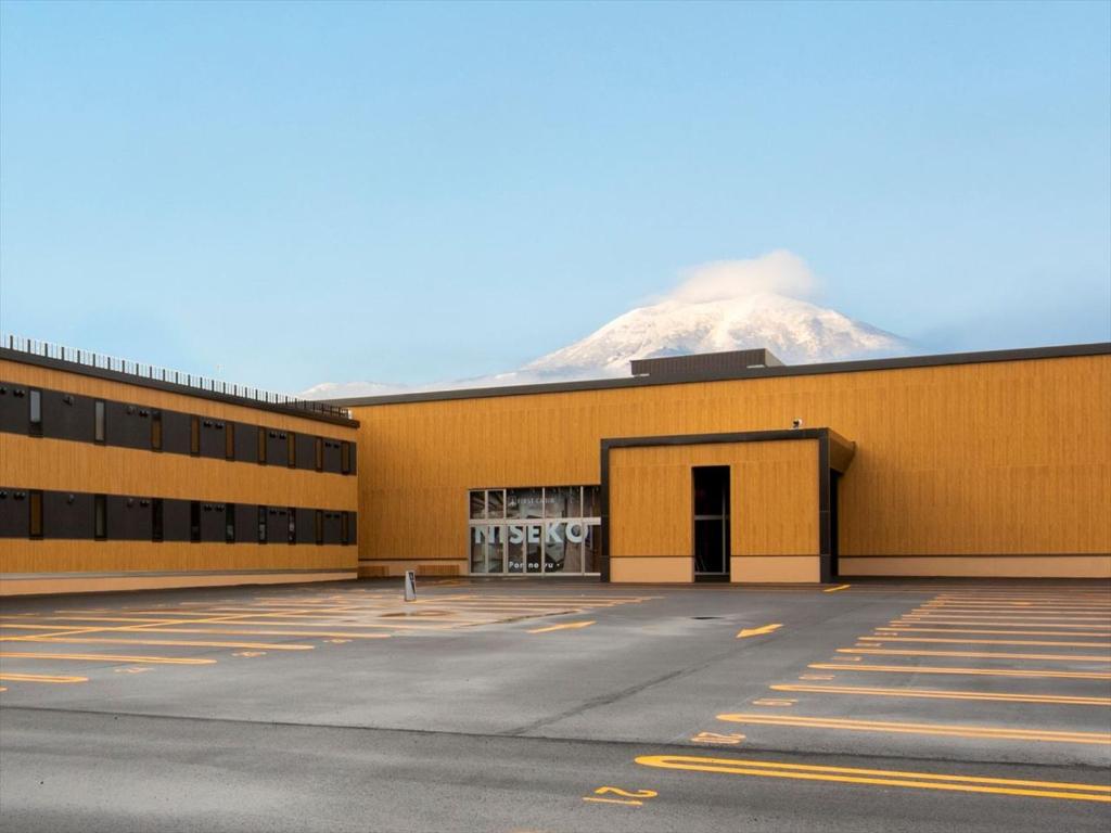 a large building with a snow covered mountain in the background at TORIFITO HOTEL&POD NISEKO in Kutchan