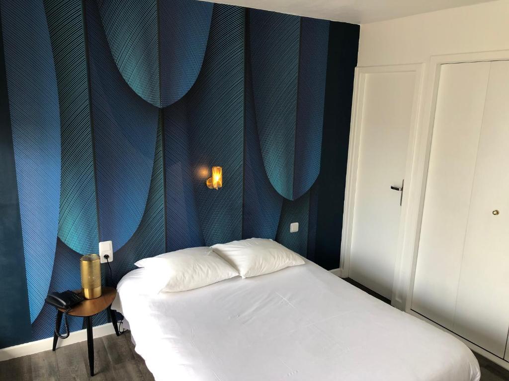 a bedroom with a bed with a blue wall at Logis Hôtel l&#39;Abricotine in Tain-lʼHermitage