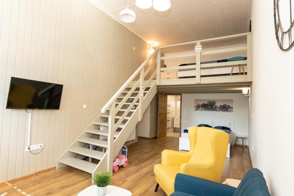 a living room with a loft bed and yellow chairs at Horský dom Apartmány in Levoča