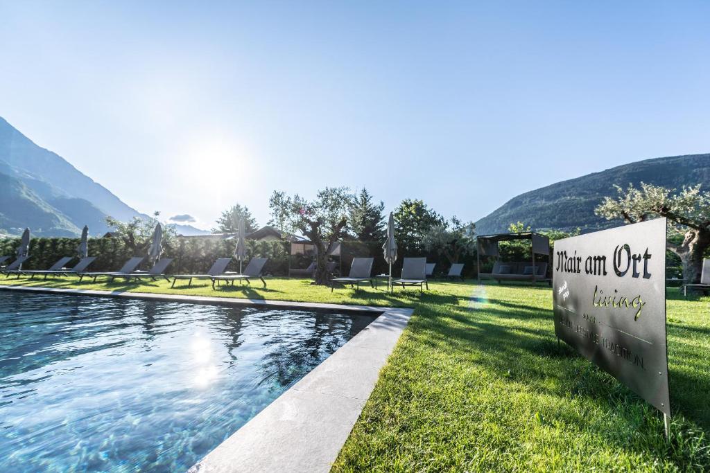 a sign in the grass next to a swimming pool at Mair Am Ort Living Hotel B&B in Parcines