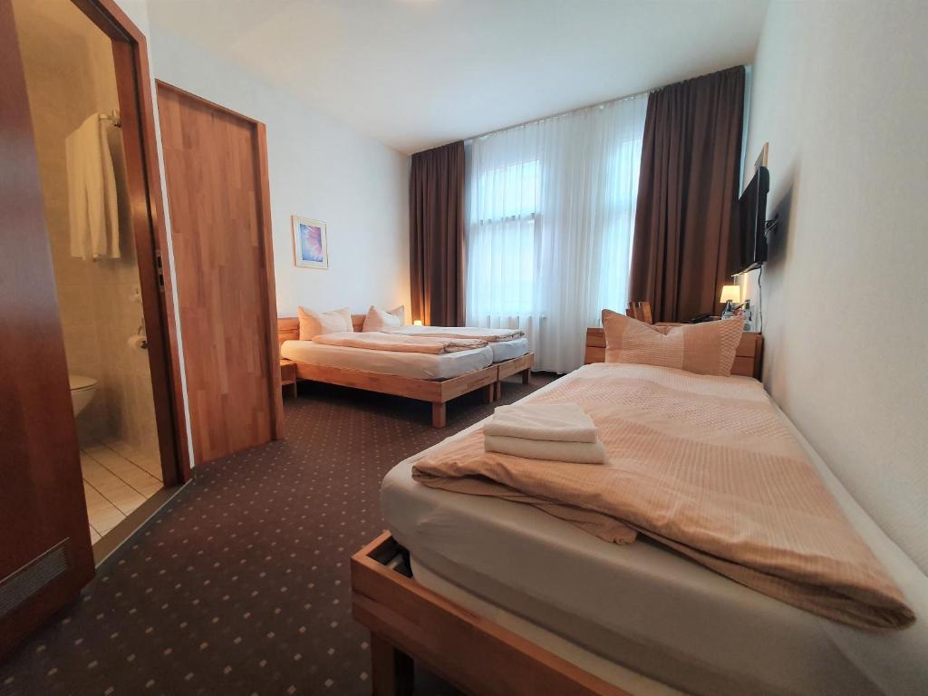 a hotel room with two beds and a bathroom at Pension am Heusteig in Stuttgart