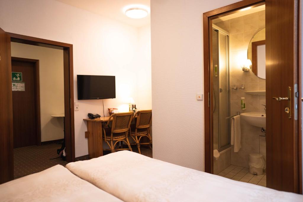 a hotel room with a bed and a bathroom at Pension am Heusteig in Stuttgart