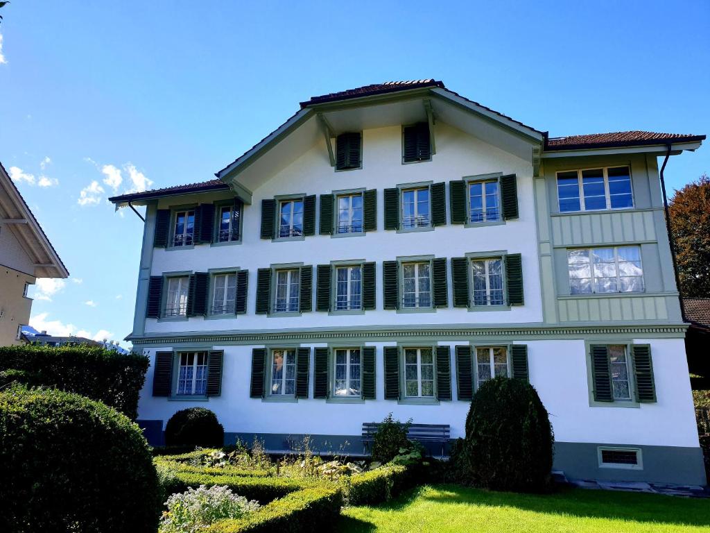 a large white house with black shutters at Interlaken Town House Sleeps 12 guests Central in Interlaken