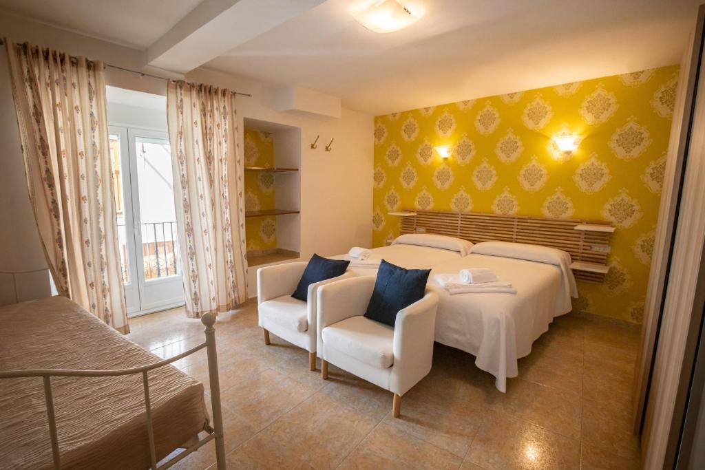 a bedroom with a bed and a couch and chairs at Hotel Rural Martin in Baños de Montemayor