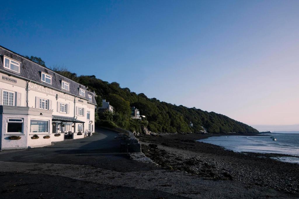 a building on a beach next to the ocean at Gazelle Hotel in Menai Bridge