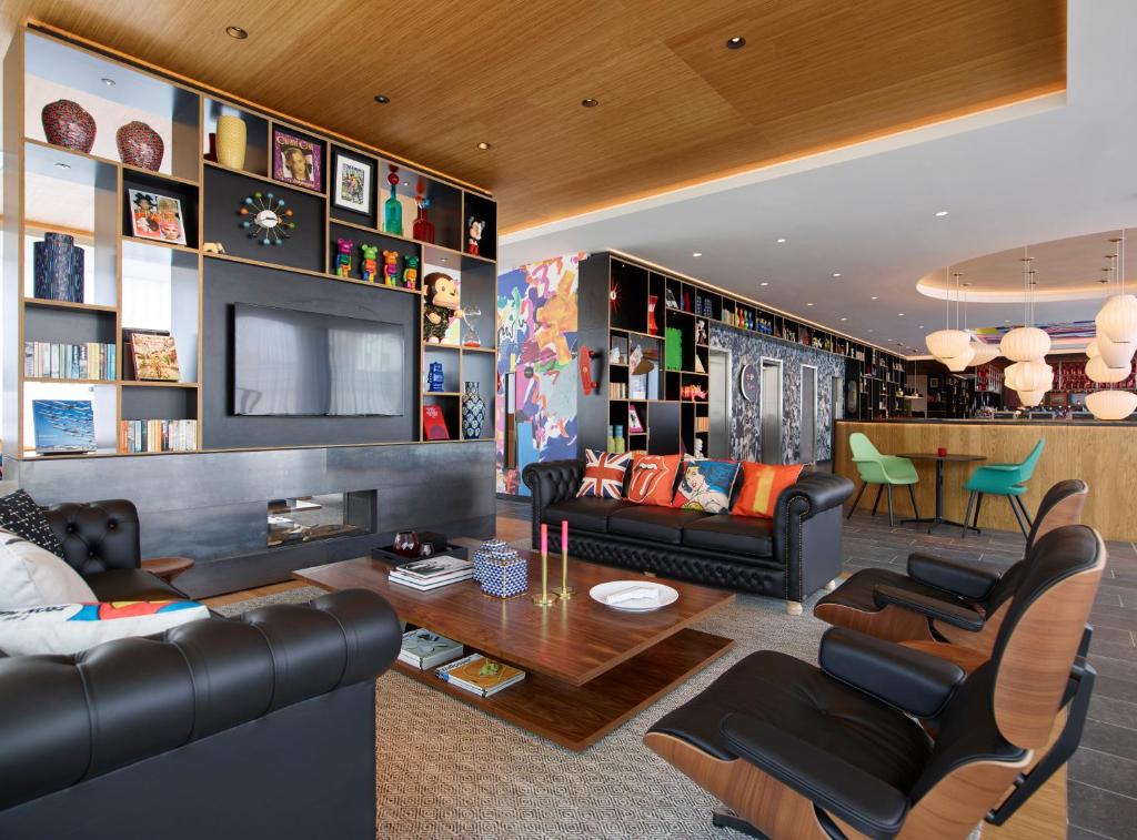 a living room with black leather furniture and a tv at citizenM London Shoreditch in London