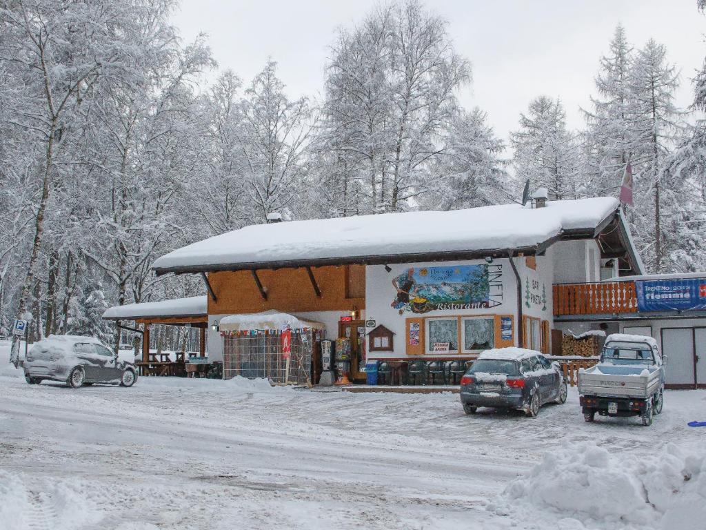una gasolinera con coches aparcados en la nieve en Albergo Pineta, en Castello di Fiemme