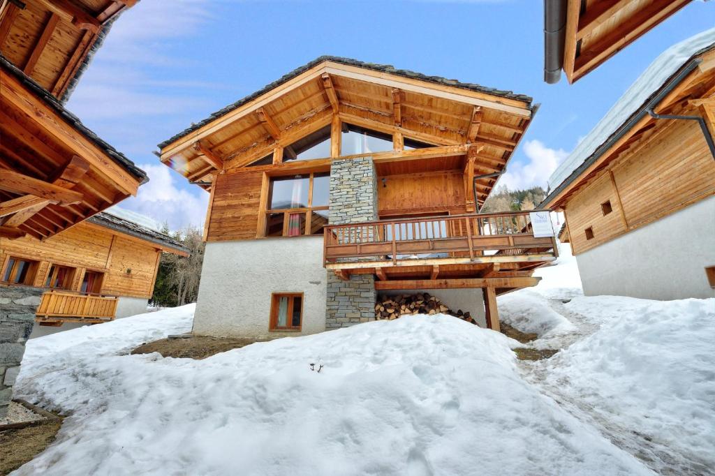 uma casa de madeira na neve com uma varanda em Chalet HERRISSON Peisey- Vallandry - Domaine Paradiski em Peisey-Nancroix