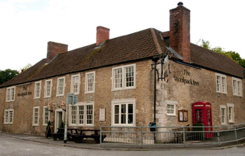 un ancien bâtiment en briques avec une cabine de téléphone rouge dans l'établissement Woolpack Inn by Greene King Inns, à Frome