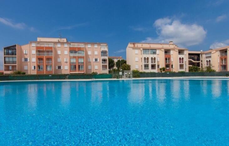 una gran piscina azul con edificios en el fondo en Joli Appartement au Lagon bleu, en Fréjus